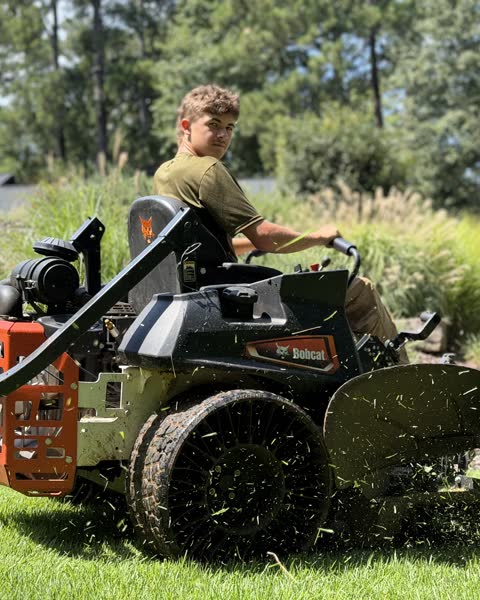Noah Smith looking back from the seat of his zero-turn mower in Athens, GA