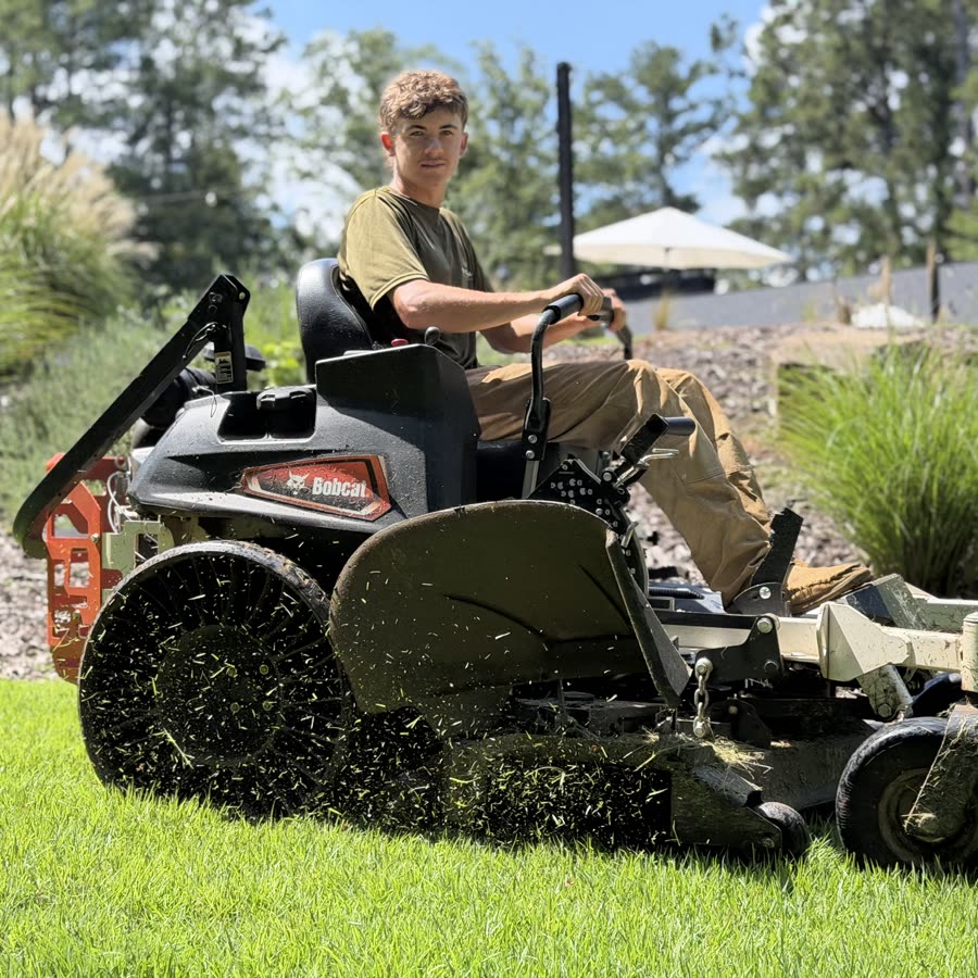 Noah Smith mowing a lawn on a zero-turn mower in Athens, GA
