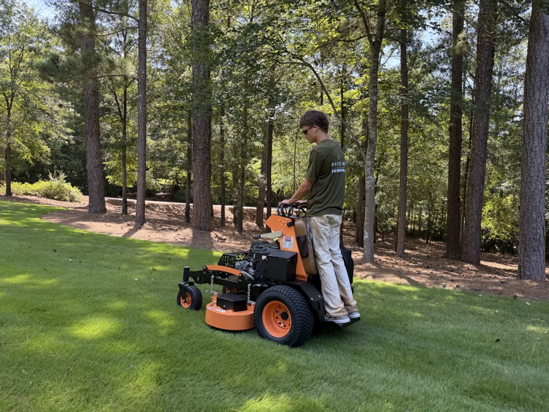 Noah Smith cutting fresh turf on the stand-on mower at a pine-lined property near Athens, GA